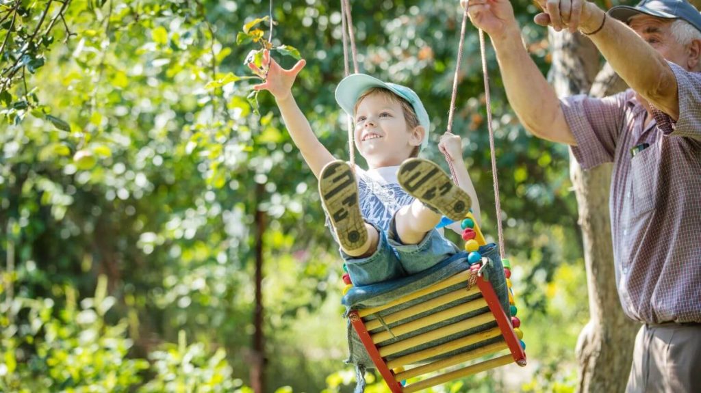 Older Retired Gentleman Pushing Great Grandson on the Swing