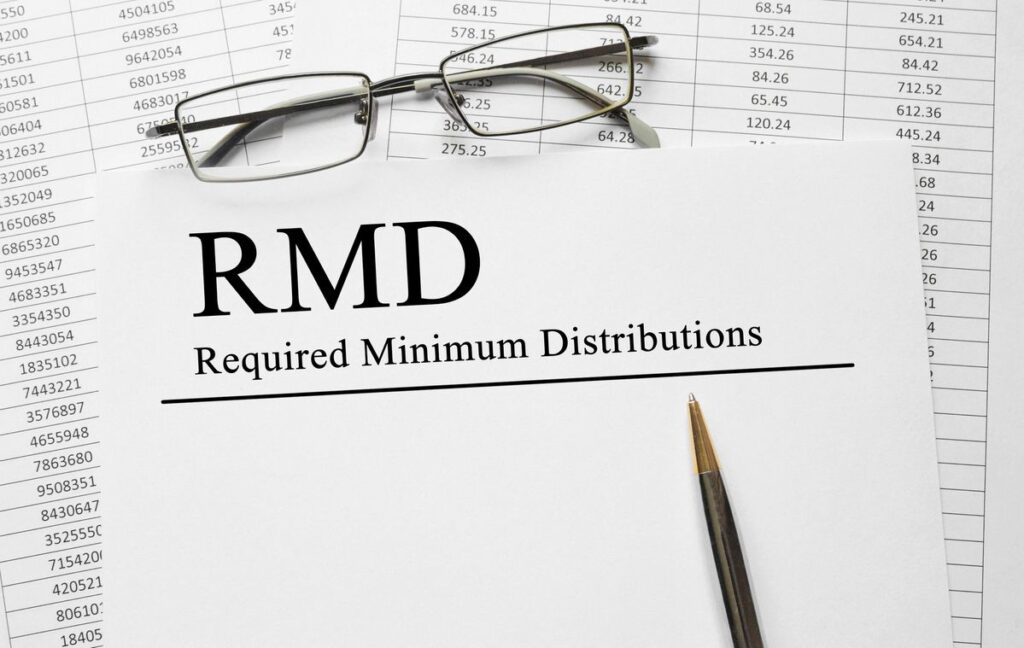 59 1/2 R and RMD withdrawal rules - RMD in bold letters on paper with spreadsheet in background.