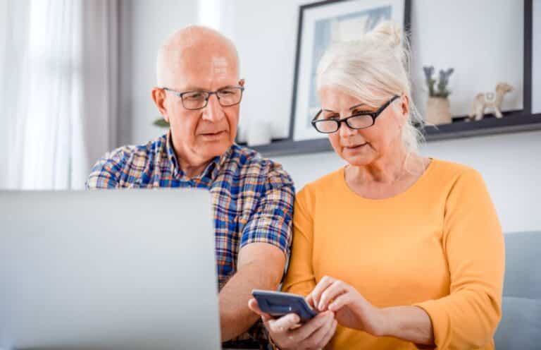 Worried older couple looking at laptop with calculator in hands - cd type annuity featured image