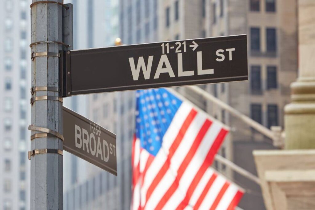 Wall street sign near stock market with american flags index annuity stock market index list