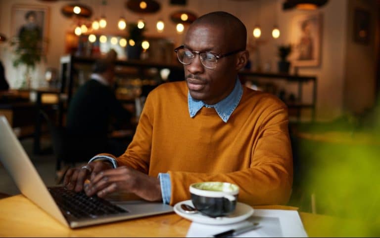 What happens during a recession featured immage of older African American male on a laptop in a Coffee Shop