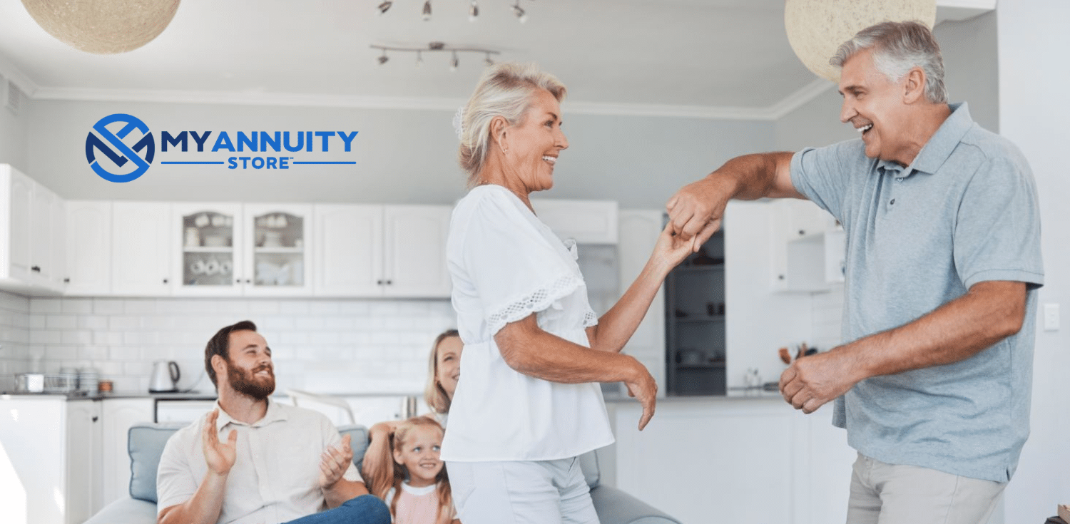 Grey haired couple dance to celebrate retirement in white outfits.